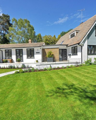 Contemporary house exterior with large manicured lawn and beautiful garden.